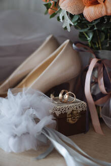 Strauß frischer Blumen und weißen Brautschuhen mit Ringen auf kleinen dekorierten Box gegen Schleier platziert - ADSF34119