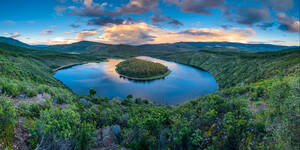 Atemberaubende Landschaft von Regenbogen über ruhigen Fluss fließt durch hügeliges Gelände gegen bewölkten blauen Himmel in Meandro Del Melero National Park in Spanien - ADSF34126