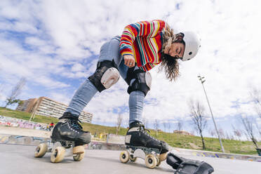 Smiling woman roller skating wearing kneepads - OCMF02351