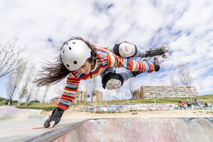 Frau zeigt ihr Können mit Rollschuhen in einem Skateboard-Park an einem sonnigen Tag - OCMF02352