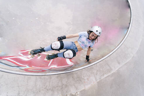 Woman wearing helmet roller skating at park - OCMF02355