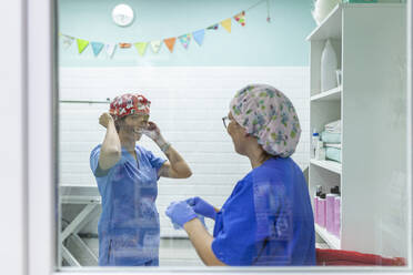 Angestellte des Gesundheitswesens in Uniform und mit Haarmützen bei der Arbeit in einer Tierklinik - MRRF01943