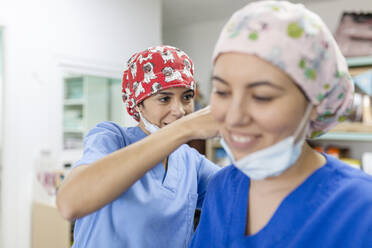 Lächelndes medizinisches Personal in Uniform und Haarmütze in einer Tierklinik - MRRF01946