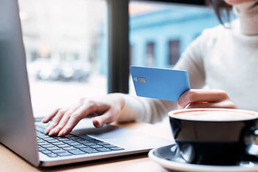 Geschäftsfrau mit Kreditkarte beim Online-Einkauf mit Laptop in einem Cafe - PNAF03411