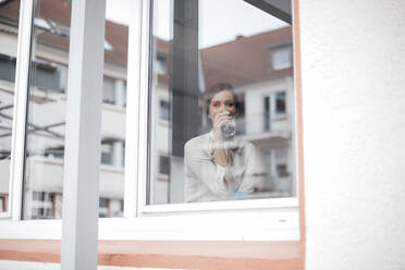 Geschäftsfrau trinkt Kaffee durch ein Glasfenster gesehen - JOSEF07675