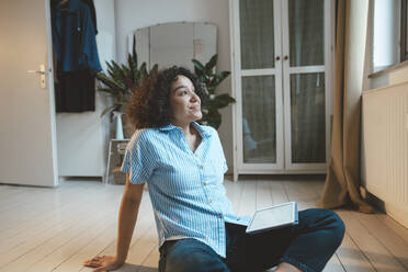 Lächelnde Frau mit Tablet-PC, die zu Hause auf der Diele sitzt - JOSEF07732
