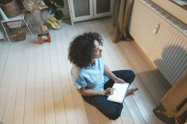 Nachdenkliche Frau mit Tablet-PC auf dem Fußboden zu Hause - JOSEF07734
