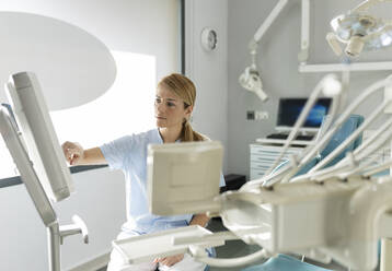 Dentist touching on monitor screen at dental clinic - JCCMF05805