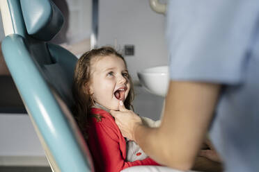 Cute little girl with mouth open looking at dentist in medical clinic - JCCMF05822