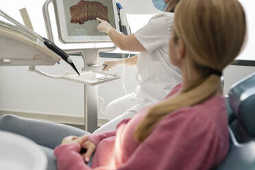 Dentist explaining teeth image on computer screen to patient in dental clinic - JCCMF05835