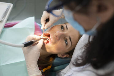 Zahnarzt, der die Zähne eines Patienten mit zahnärztlicher Ausrüstung in einer medizinischen Klinik untersucht - JCCMF05839