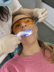 Zahnarzt beim Trocknen von Zahnfüllungen mit Aushärtungslicht in einer medizinischen Klinik - JCCMF05861