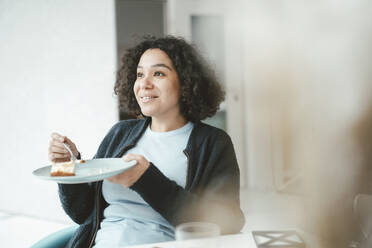 Smiling woman eating cake at home - JOSEF07862