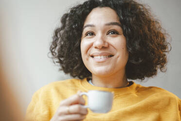 Smiling beautiful woman with curly hair holding coffee cup - JOSEF07876