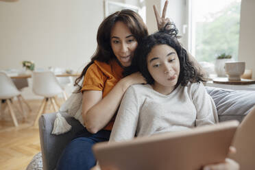 Frau und Tochter strecken ihre Zungen heraus und machen ein Selfie über einen Tablet-PC zu Hause - JOSEF07949