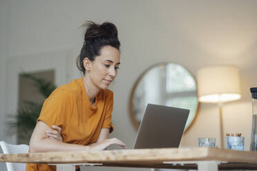 Woman using laptop in living room at home - JOSEF07960