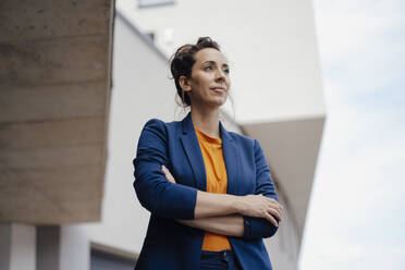 Thoughtful businesswoman with arms crossed outside building - JOSEF07971