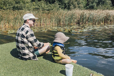 Vater mit kleinem Sohn beim Angeln im Fluss an einem sonnigen Tag - ACTF00182