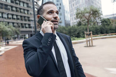 Businessman talking on phone outdoors - JSRF01960
