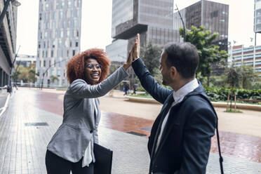 Two business colleagues high-fiving outdoors - JSRF01963