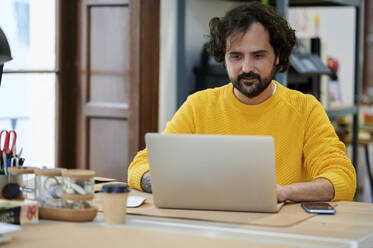 Businessman using laptop at desk in office - KIJF04392