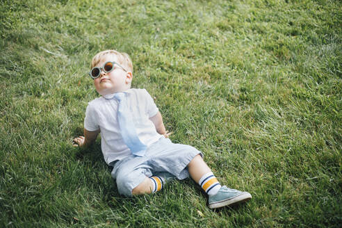 Junge mit Sonnenbrille und Krawatte sitzt im Gras - ACTF00191
