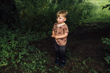 Boy wearing rubber boots standing in park - ACTF00198