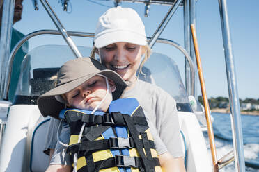 Smiling mother with son wearing life jacket in speedboat on sunny day - ACTF00200