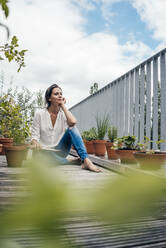 Thoughtful woman with tablet PC sitting in balcony - JOSEF07996