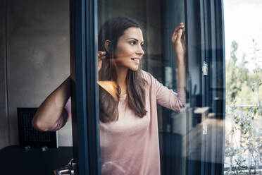 Beautiful smiling woman seen through glass window - JOSEF08027