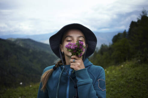 Caucasian girl smelling flowers on mountain range - TETF01581