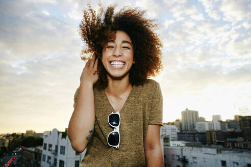 Portrait of smiling Hispanic woman on urban rooftop at sunset - TETF01583