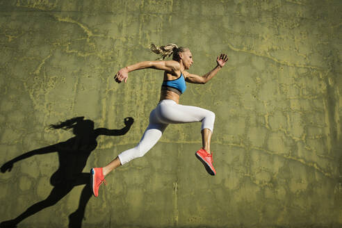 Athlete woman jumping against wall - TETF01588