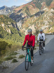 Vereinigte Staaten, Utah, American Fork, Lächelnder Mann und lächelnde Frau fahren mit dem Fahrrad auf einer Bergstraße - TETF01596
