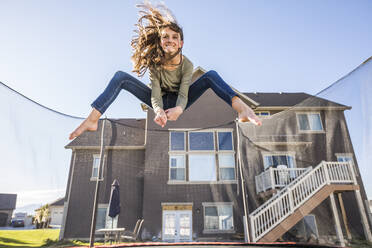 Mädchen (12-13) springt auf dem Trampolin vor dem Haus - TETF01613