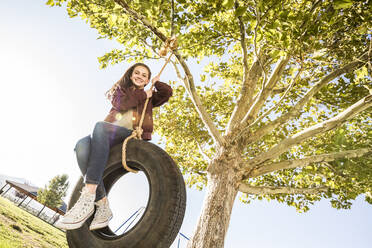 Smiling girl (12-13) on tire swing in garden - TETF01616