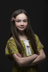 Studio-Porträt eines lächelnden Mädchens (10-11) in grünem Kleid mit Blume im Haar - TETF01622