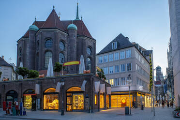 Germany, Bavaria, Munich, Stores in front of Saint Peter's Church at dusk - MAMF02085