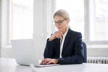 Businesswoman working on laptop at work place - JOSEF08032