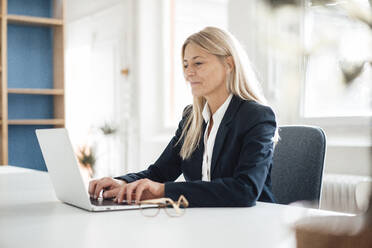 Blonde Geschäftsfrau mit Laptop am Schreibtisch bei der Arbeit - JOSEF08037