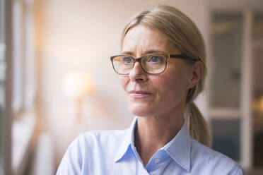 Contemplative businesswoman with eyeglasses at work place - JOSEF08066