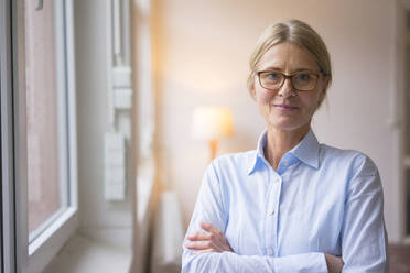 Confident businesswoman with arms crossed at work place - JOSEF08067