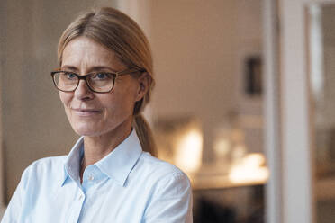 Thoughtful businesswoman with eyeglasses at work place - JOSEF08075