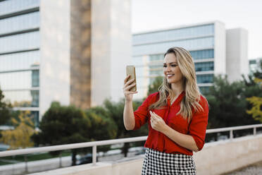 Smiling businesswoman on video call over smart phone in city - DCRF01043