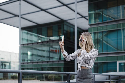 Geschäftsfrau nimmt Selfie auf Smartphone vor Bürogebäude - DCRF01047