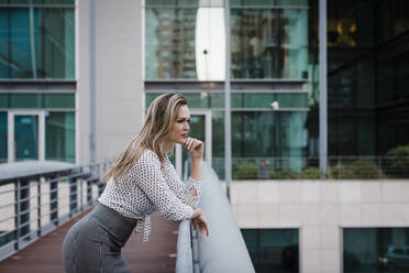 Businesswoman leaning on railing on office balcony - DCRF01049