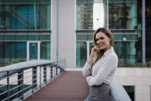 Lächelnde Geschäftsfrau auf dem Balkon eines Büros - DCRF01052
