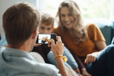 Mann fotografiert Frau und Sohn mit Smartphone zu Hause - JOSEF08081