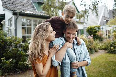 Smiling father and mother carrying son at backyard - JOSEF08108