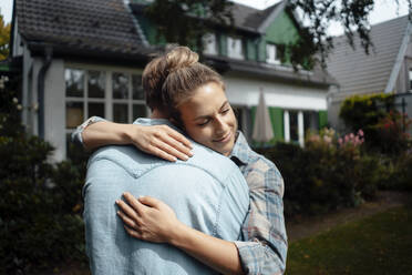 Lächelnde Frau umarmt ihren Freund im Hinterhof - JOSEF08134